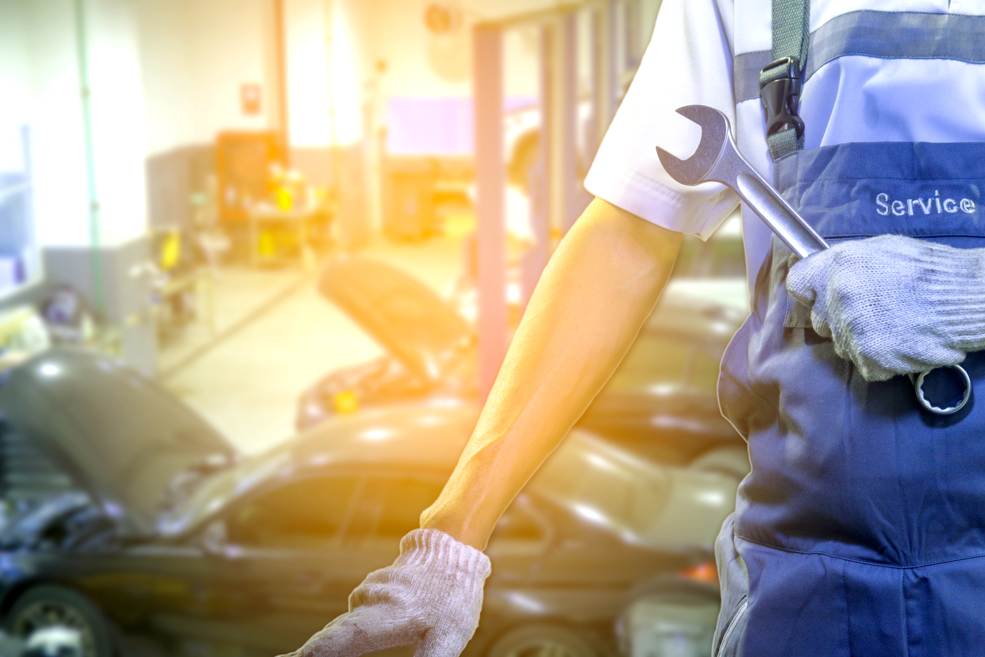 Car Mechanic With Wrench On Blurred Auto Repair Garage Background